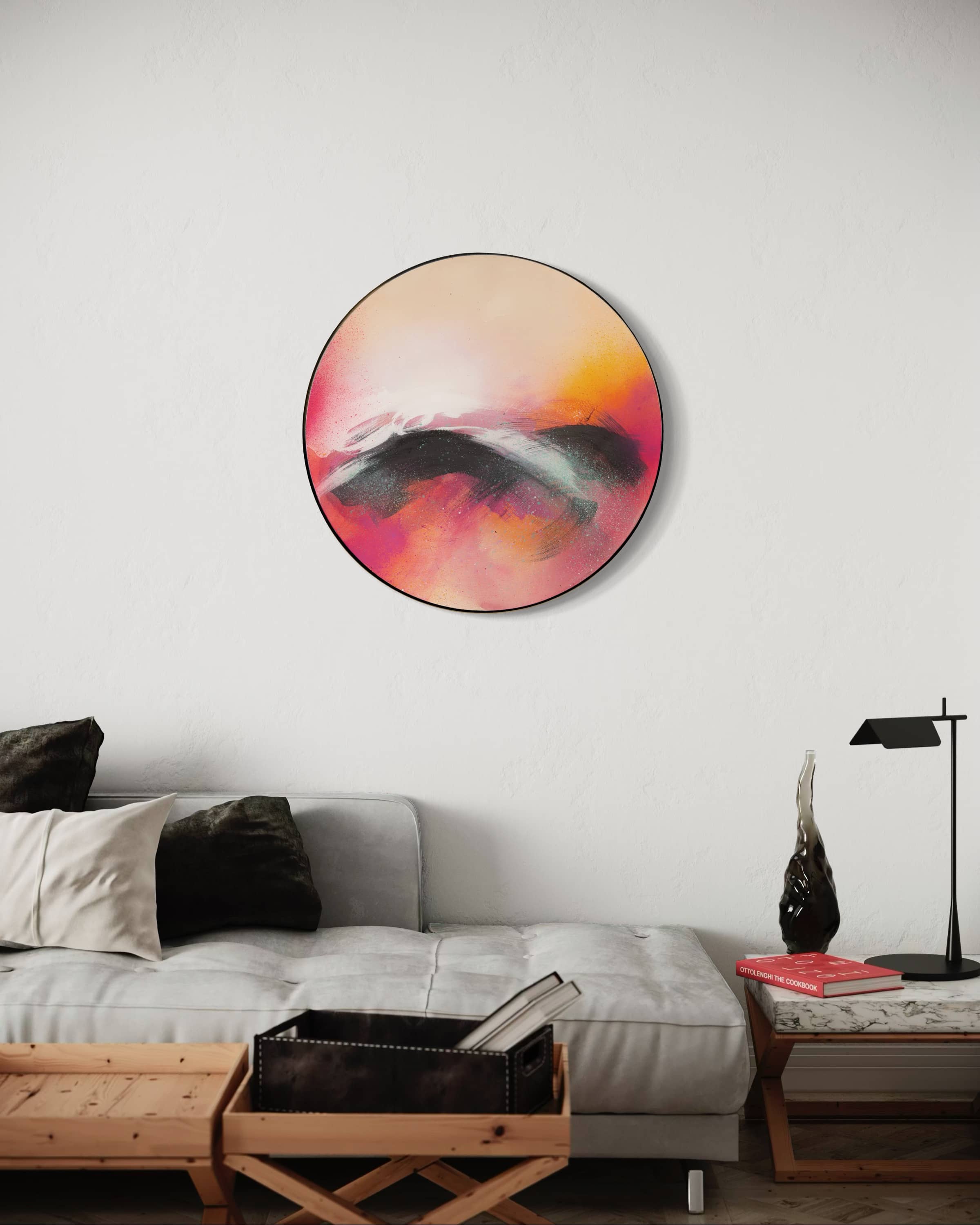 “Optimistic” by Kate Mayer, a round abstract painting, hangs above a modern gray sofa in a handmade metal float frame.