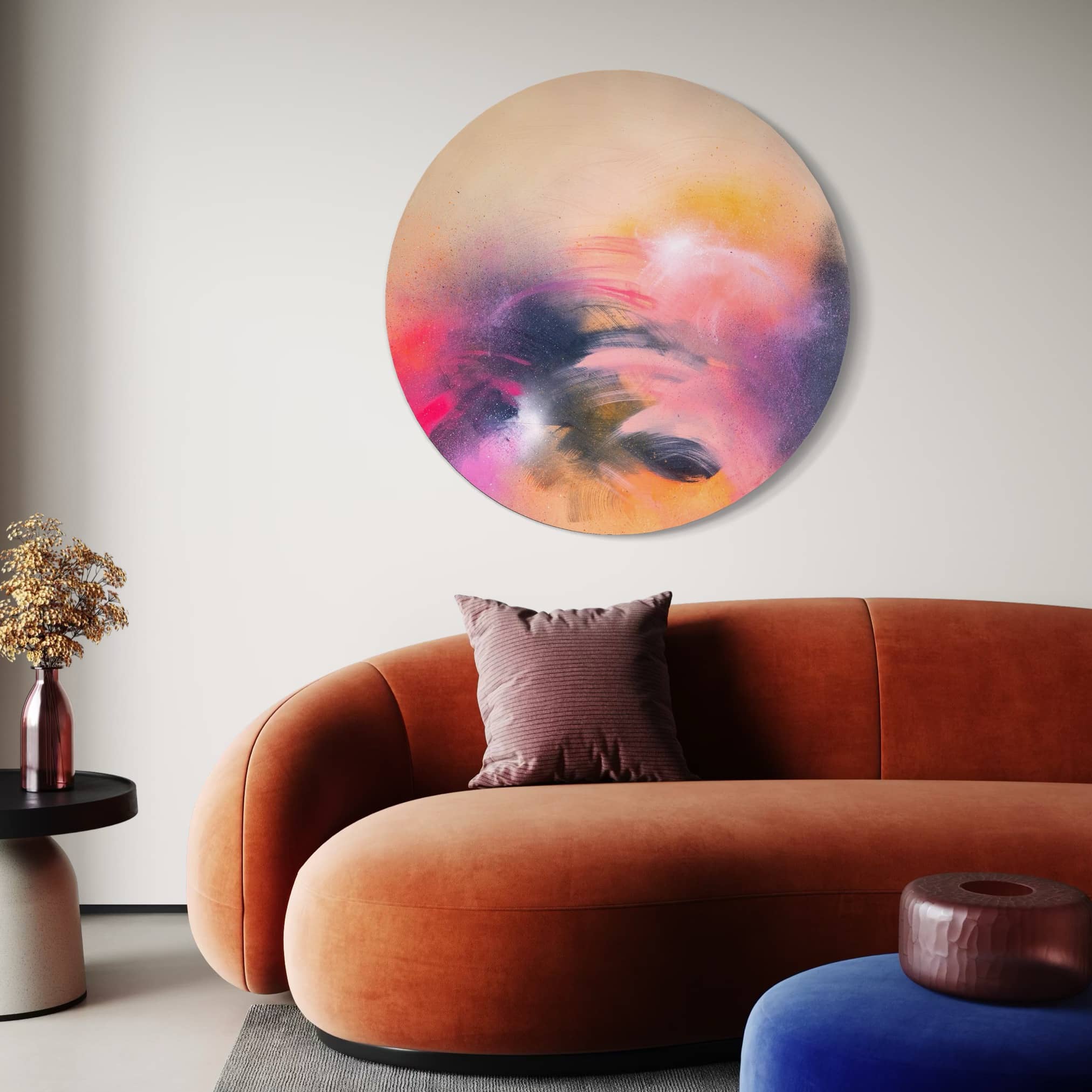 A modern living room with a curved orange sofa, Kate Mayer’s "A Star is Born" painting, and a side table with dried flowers.