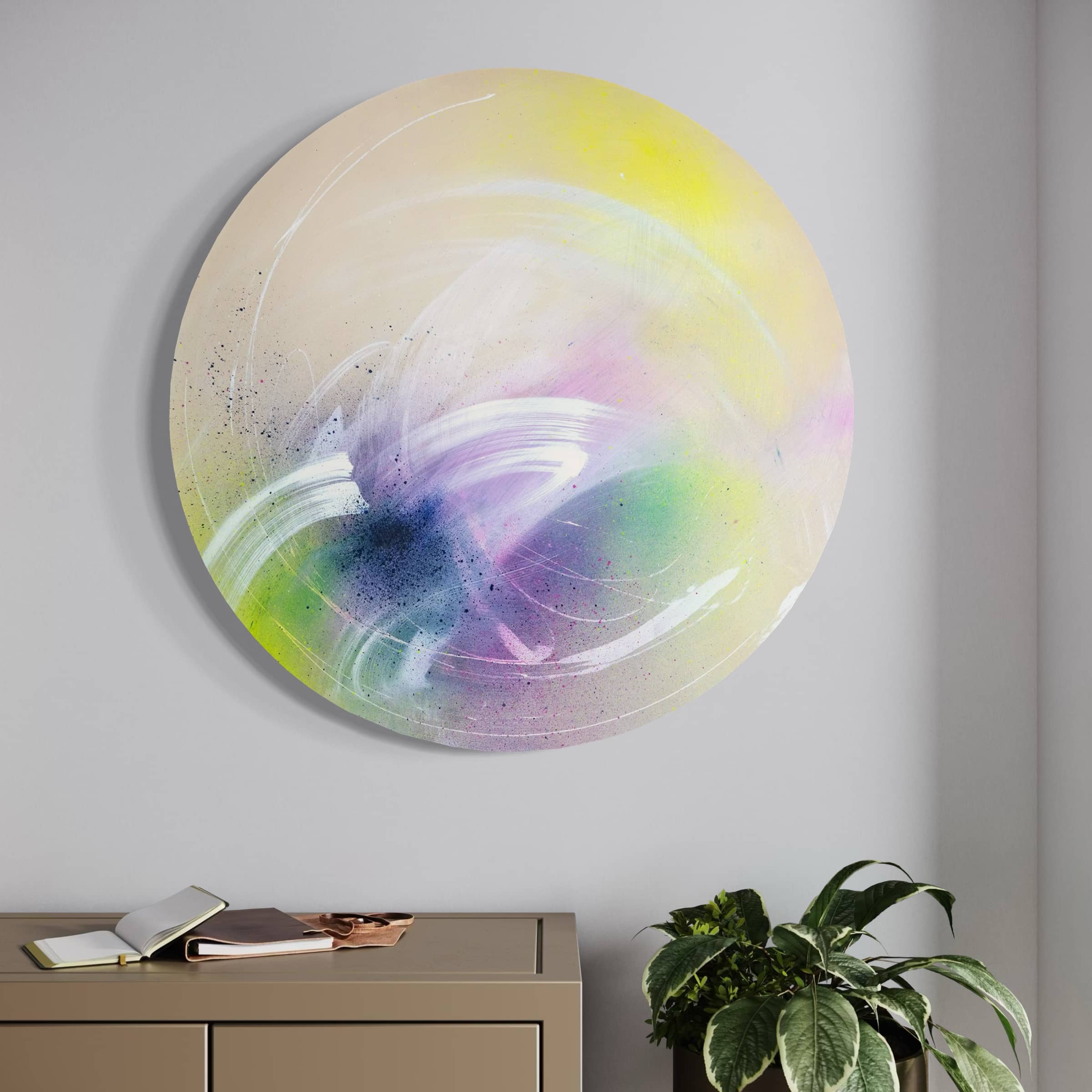 Kate Mayer's "I Believe In Miracles" abstract painting with soft swirls is displayed above a cabinet with plants and an open book.