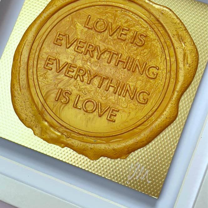 Kate Mayer’s Sealed Intention for LOVE is a framed artistic piece featuring a bespoke wax seal imprint that reads, "LOVE IS EVERYTHING, EVERYTHING IS LOVE," elegantly displayed in a white shadow frame.