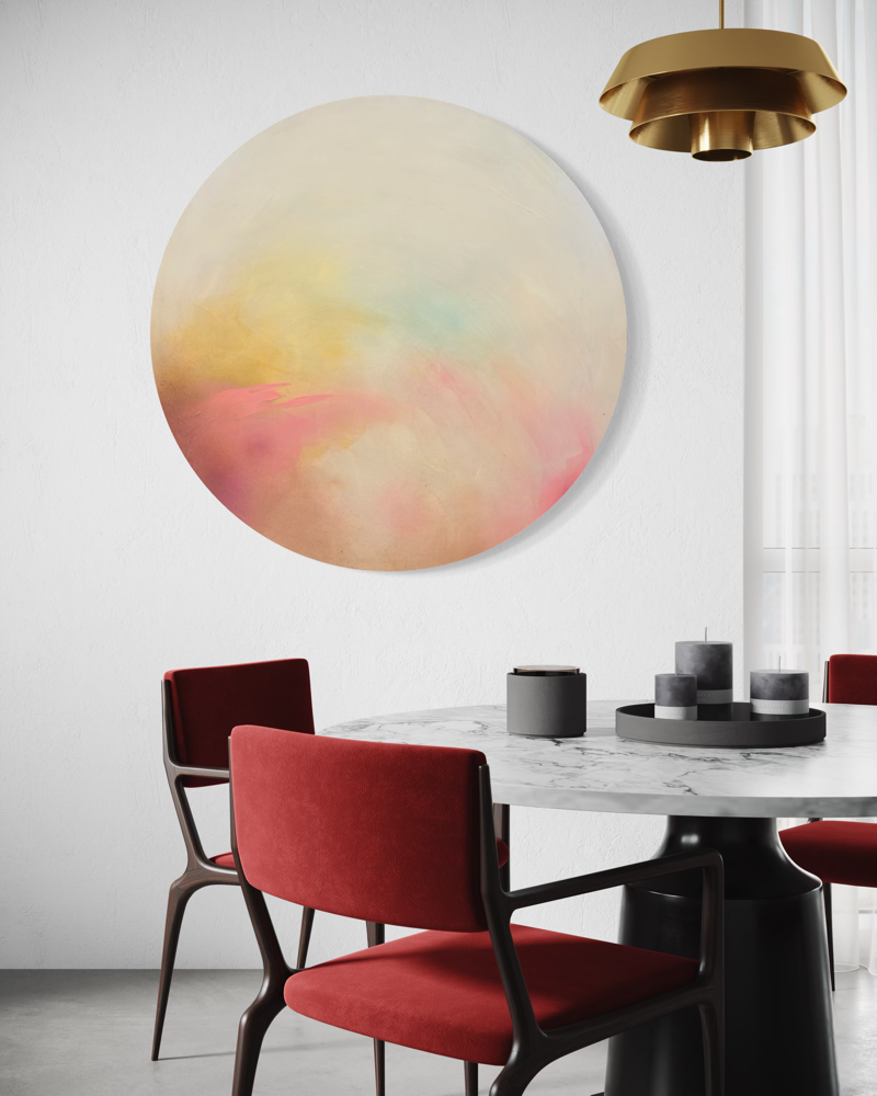 The Afterglow of Connection“ by Kate Mayer hangs on a white wall above a marble table with red chairs and gold light.