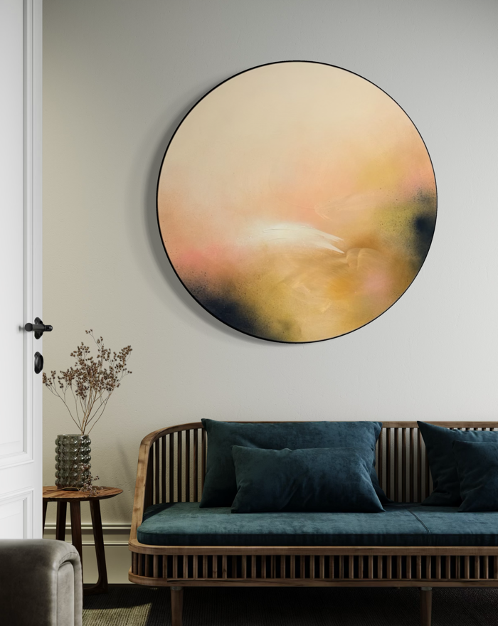 Friend“ by Kate Mayer, a round acrylic on plywood, hangs above a wooden sofa with blue cushions in a modern space.