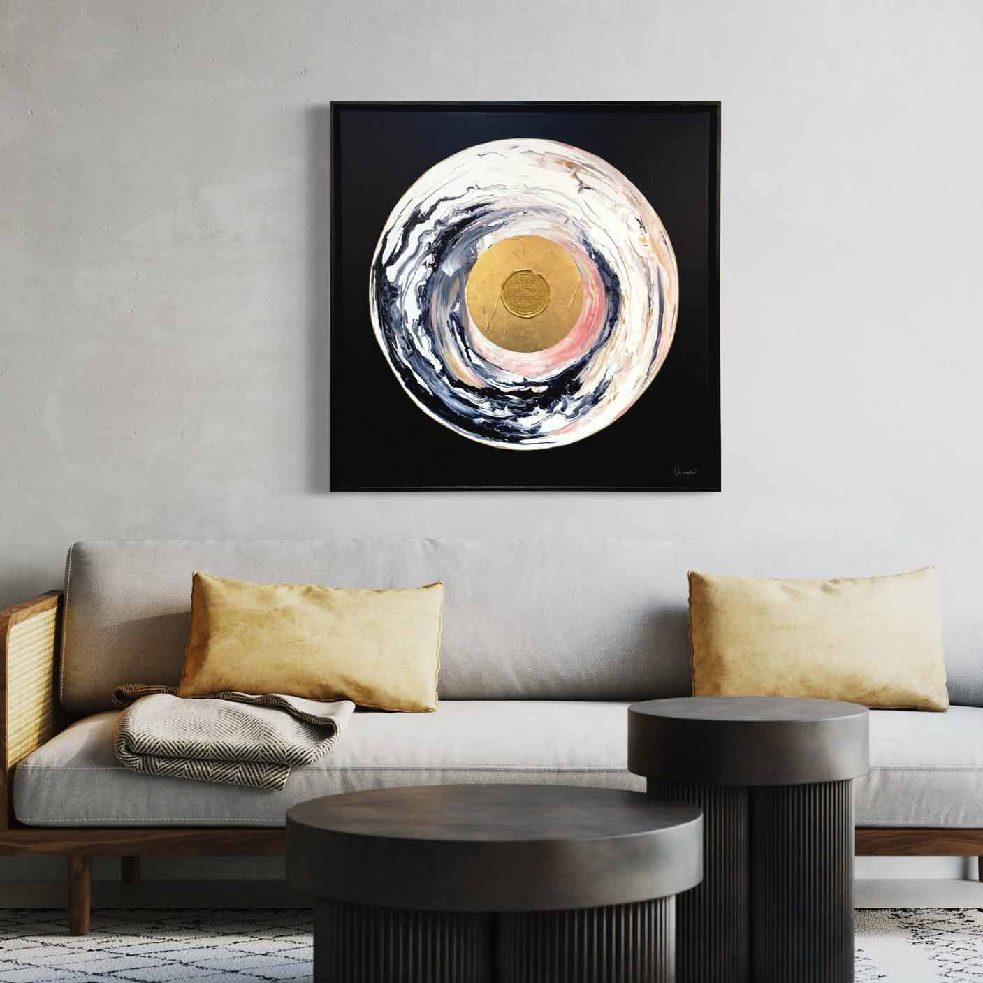 A minimalist living room with a grey sofa, beige cushions, two round black coffee tables, and the original painting "Love Sublime" by Kate Mayer featuring acrylic and gold leaf.