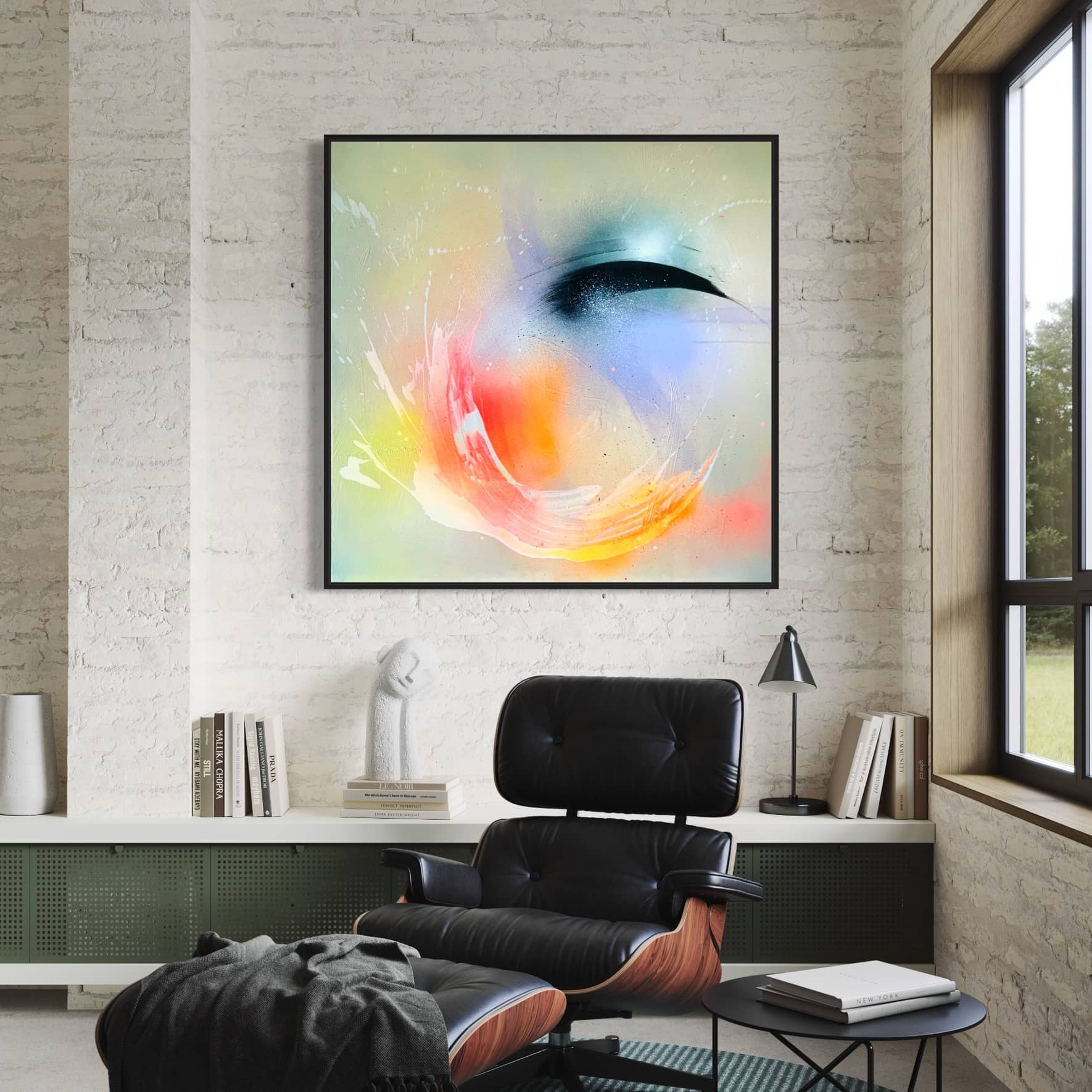 A modern living room showcases "Eternal Vitality," an original painting by Kate Mayer, crafted with acrylic and spray paint. It graces the wall above a black leather chair, while books and a sculpture add elegance to the nearby shelf.