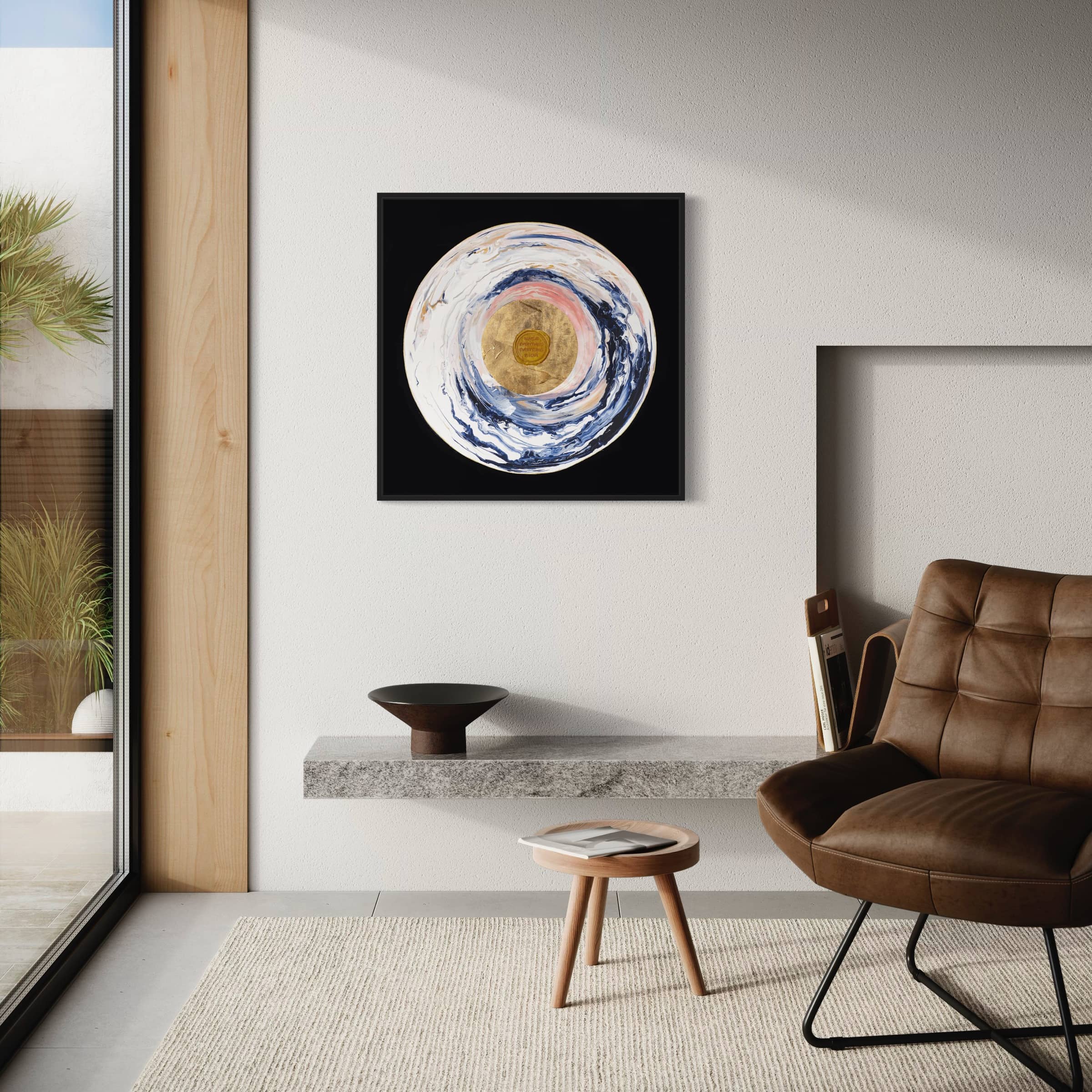 A modern living room with a brown leather chair, a small round wooden table, and "Love Sublime," an original painting by Kate Mayer that features acrylic and gold leaf, on the wall above a floating shelf.